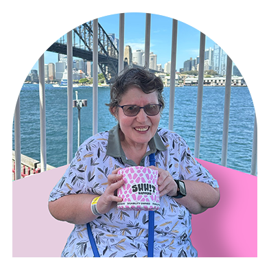 Happy woman holding eco-friendly pink toilet paper by Shh!t Happens in front of Sydney Harbour — Australian-made recycled toilet paper and tissues from a disability-owned brand
