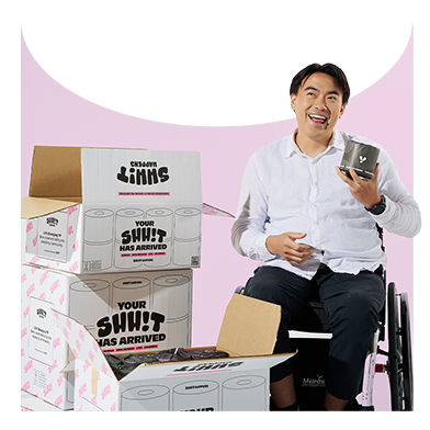 Man in wheelchair holding black wipes by Shh!t Happens surrounded by eco toilet paper boxes — sustainable bulk toilet paper and tissues from an Australian disability-led company.